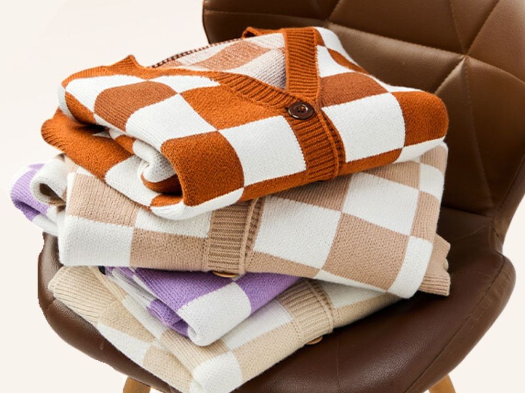 different color checkered vneck cardigans stacked on a chair