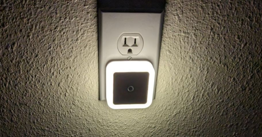 small white square nightlight plugged into wall outlet