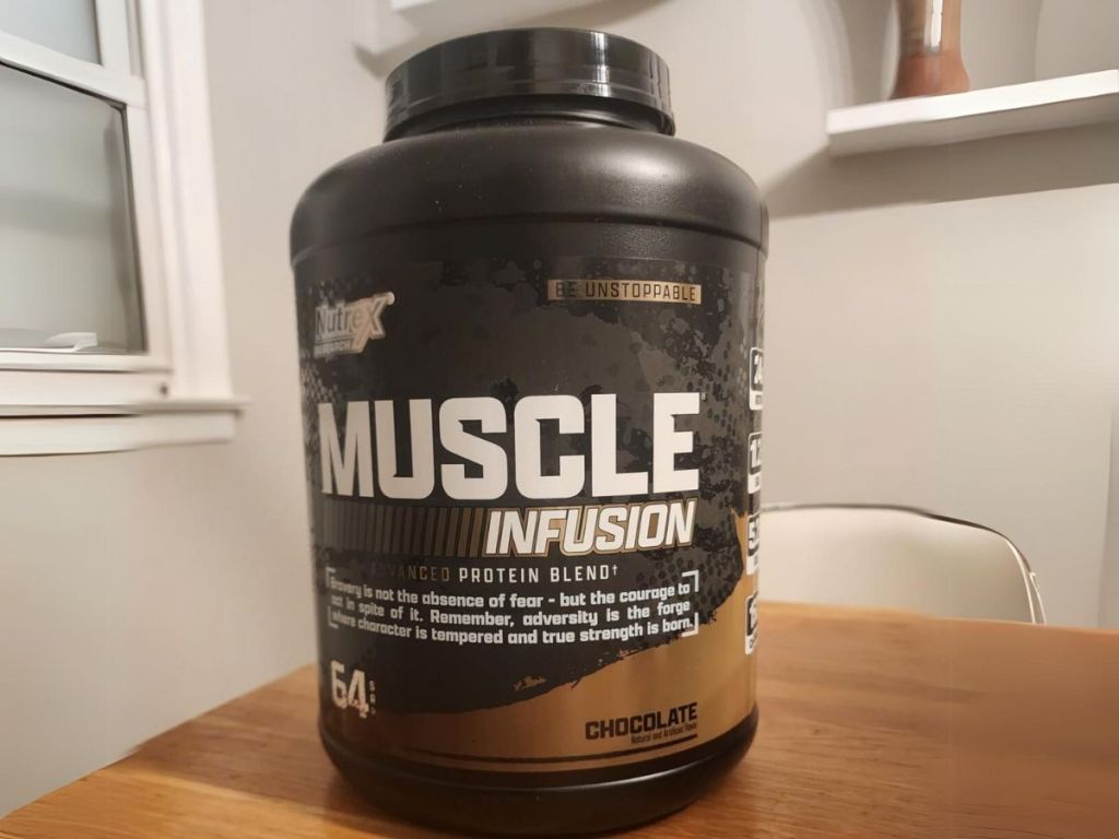 large container of Nutrex Research Muscle Infusion Advanced Whey Protein Blend Powder in Chocolate sitting on a table