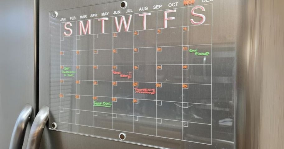 clear acrylic calendar on a stainless steel fridge with monthly appointments and reminders