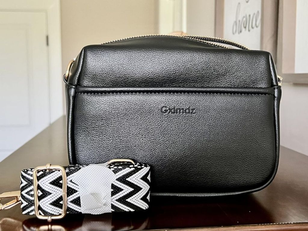 black purse with black white pattern strap
