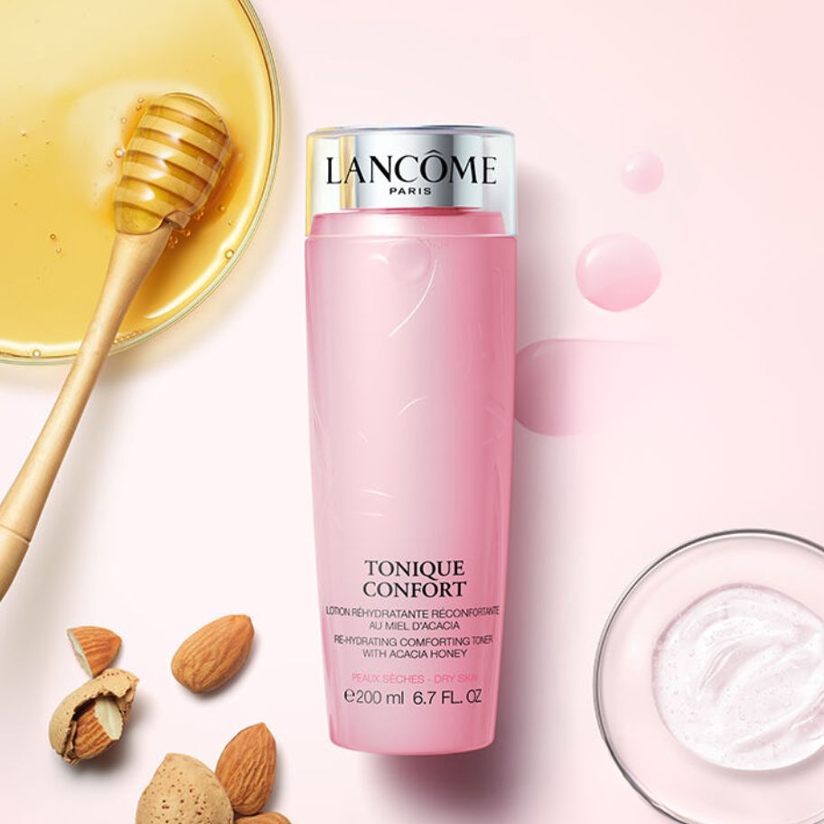 pink bottle of Lancome Tonique Confort Hydrating Toner with honey, almonds and serum beside of it