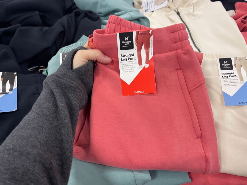 hand holding a pink pair of pants at Sam's Club with more behind it