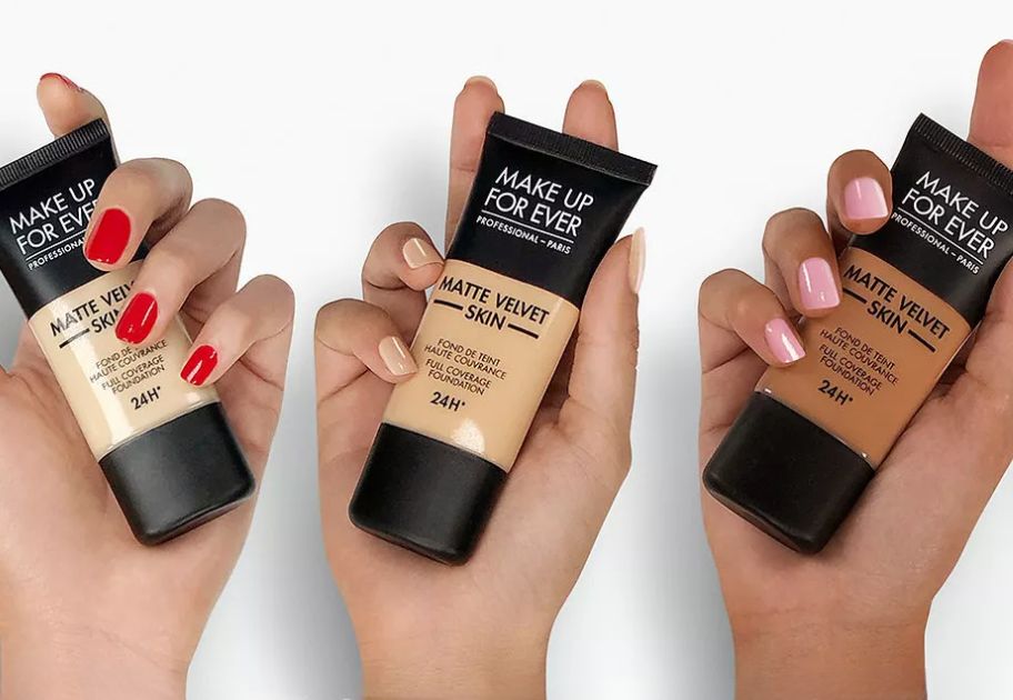 3 women's hands holding tubes of Make Up For Ever Matte Velvet Skin Full Coverage Foundation 