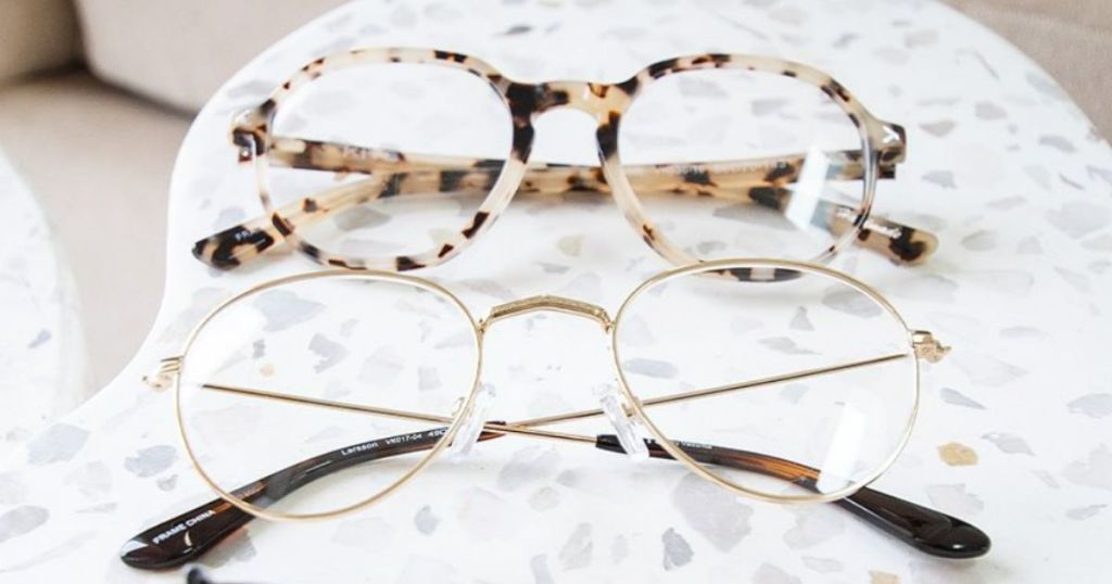 2 pairs of eyeglasses laying on marble looking side table