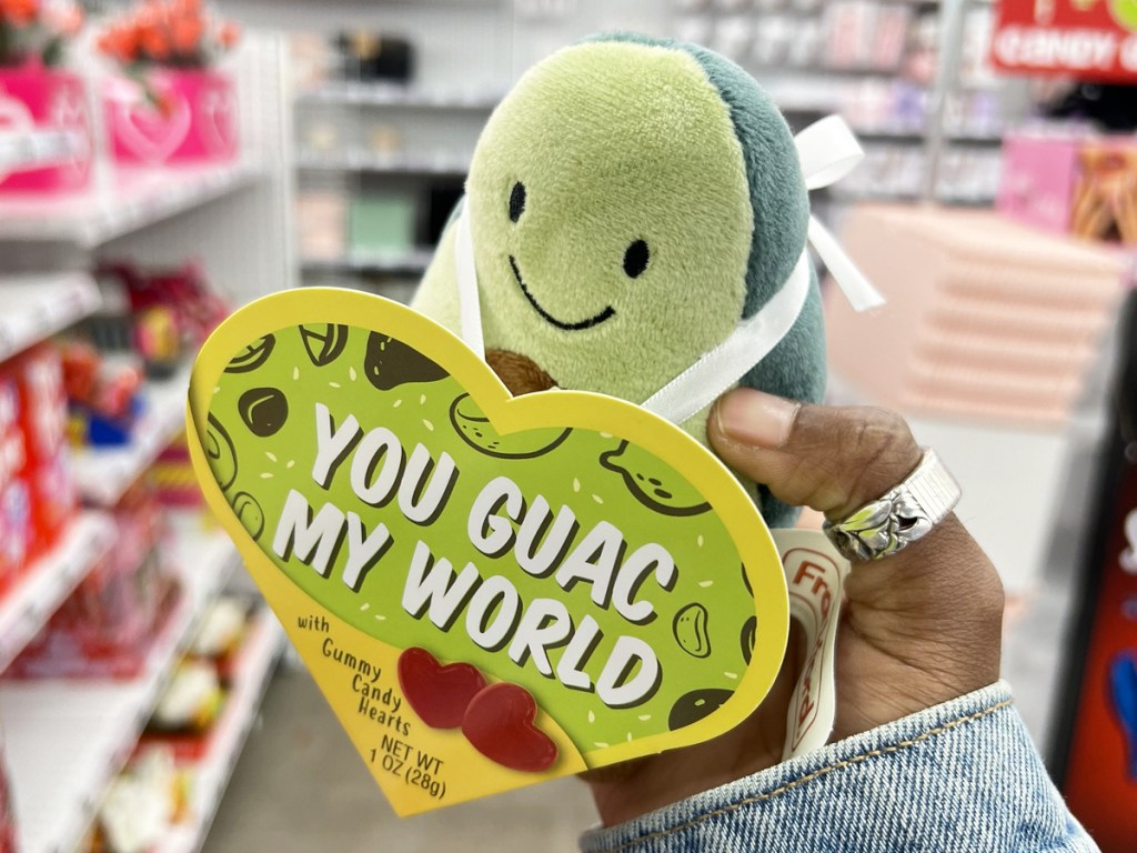 holding up a plush avocado that says "you guac my world"