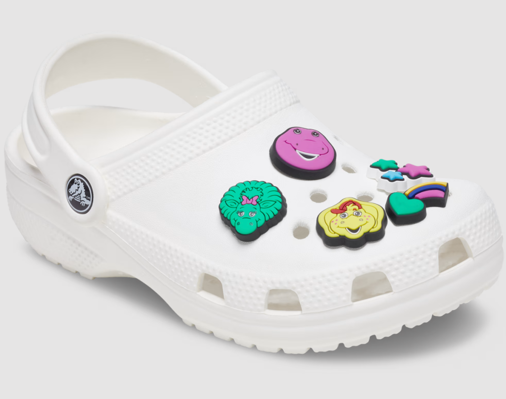 a white Barney Crocs shoe with Jibbitz accessories