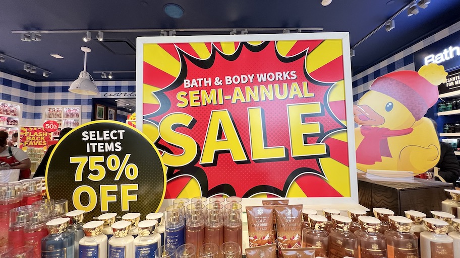 bath and body works semi annual sale sign at store with bottles of lotion and soap