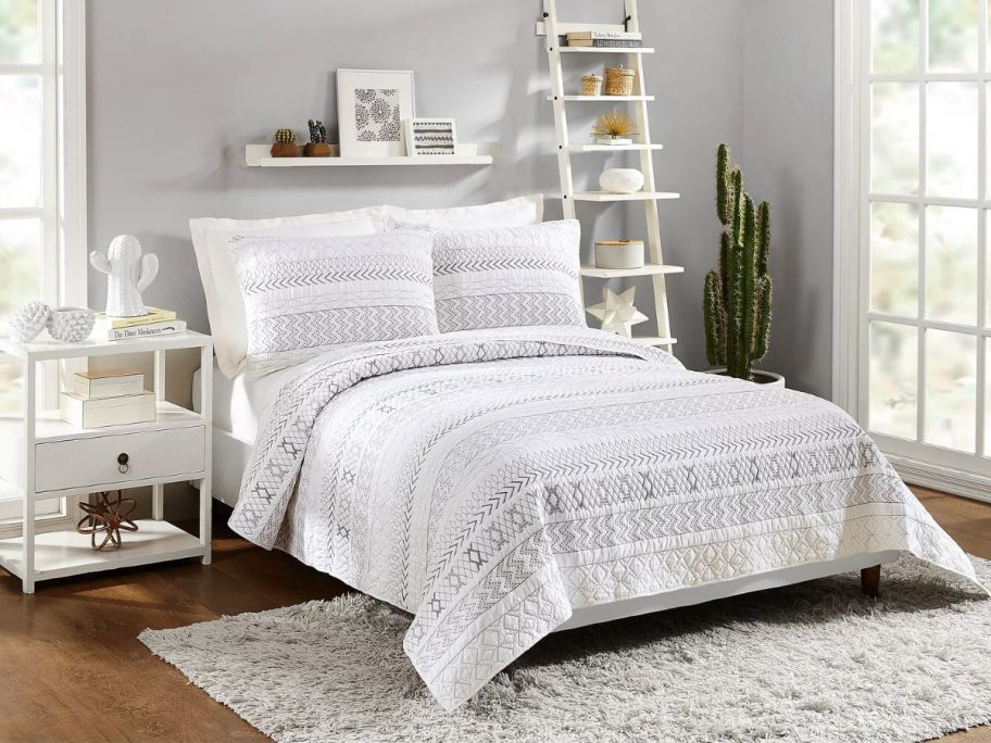 a queen bed with a white and grey striped comforter set 