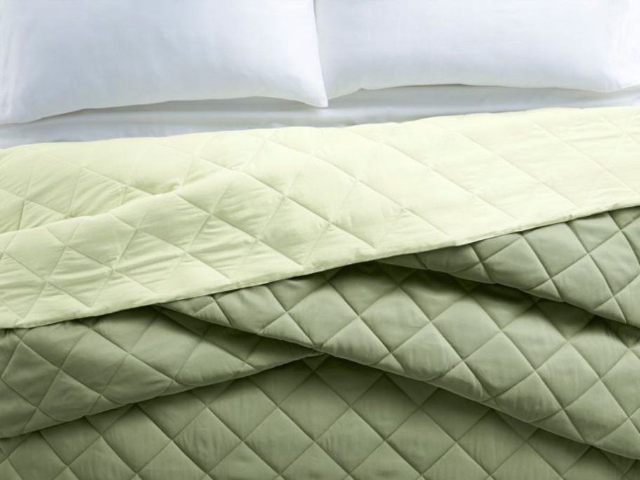 reversible green/light green lightwieght down alternative comforter on a bed