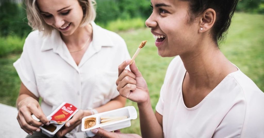 2 women eating Biscoff & Go snack packs