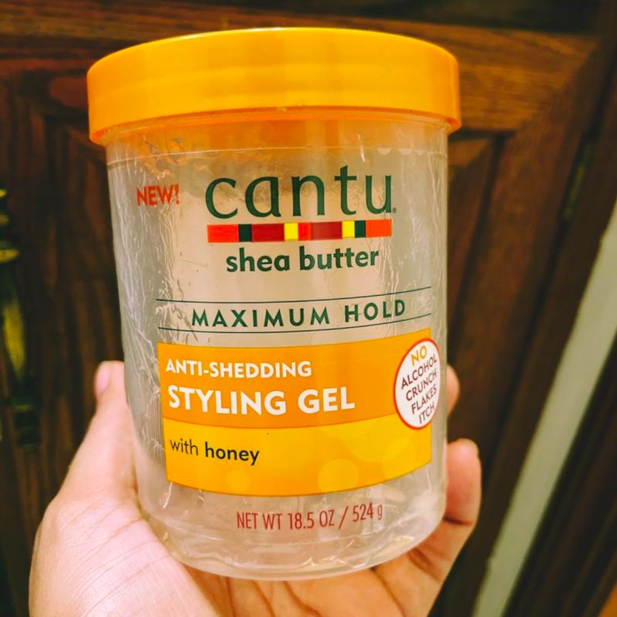 a woman's hand holding a jar of styling gel