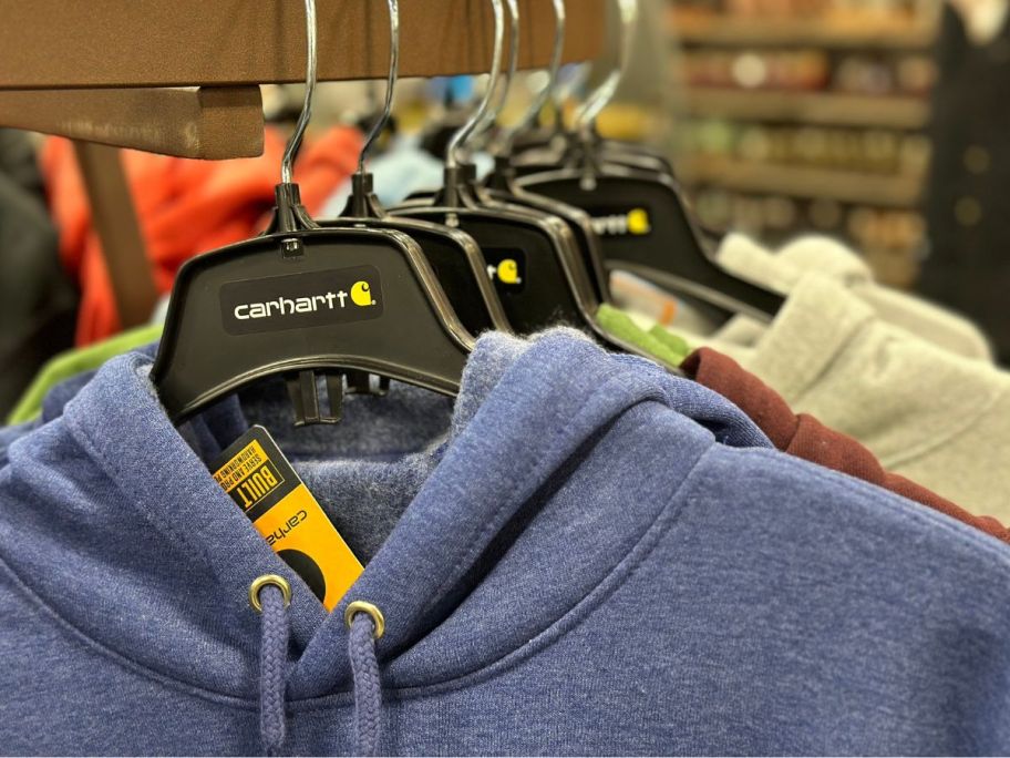 A rack of Carhartt hoodies on hangers