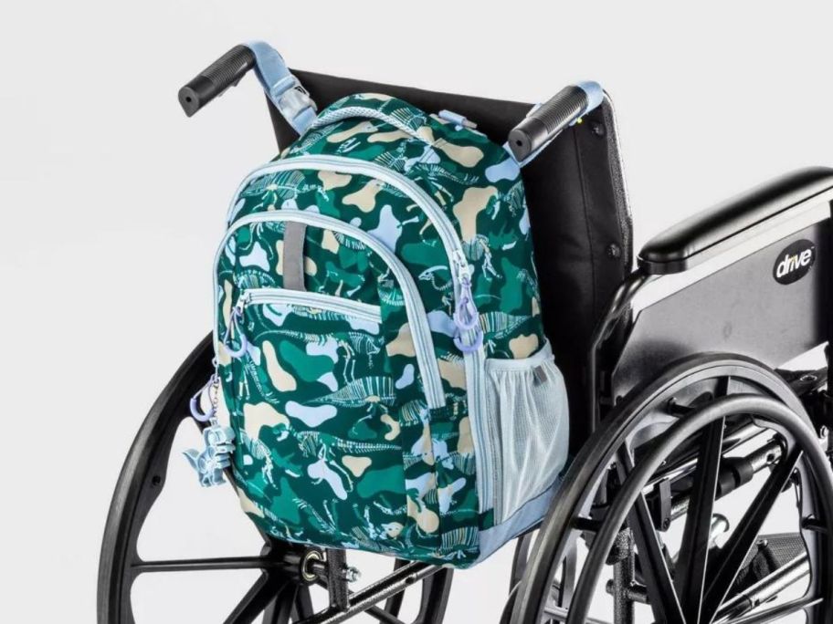 Cat & Jack Kids' Adaptive 17" Dino Camo Backpack on the back of a wheelchair