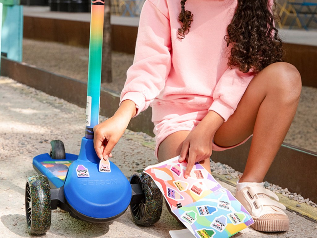 Child putting stickers on crayola scooter