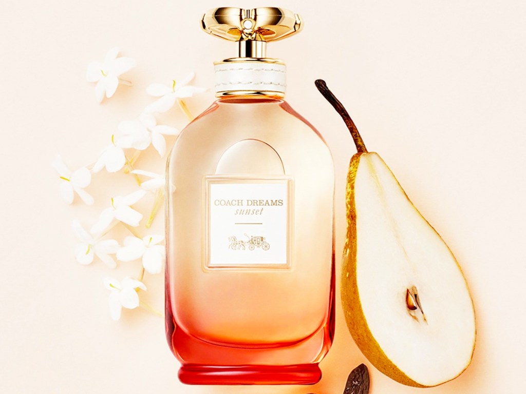 bottle of coach perfume near pear slices and white flowers