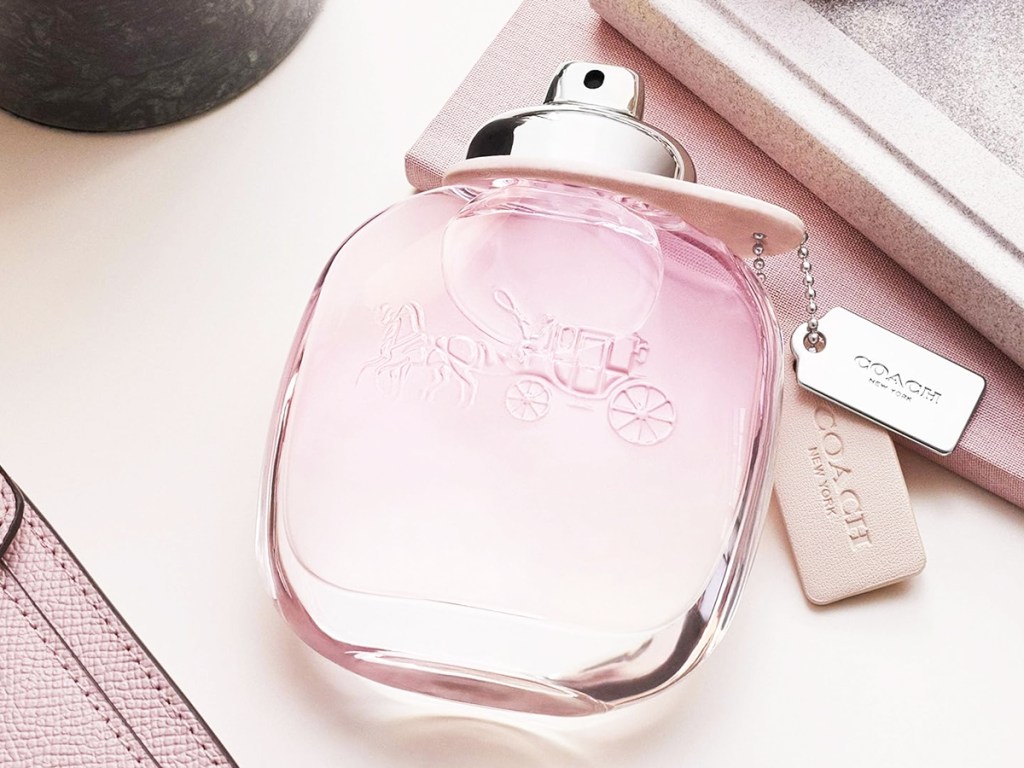 pink bottle of coach perfume on its side on a vanity