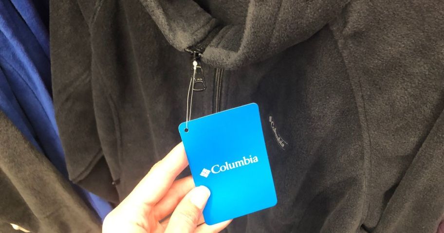 Hand touching the sales tag on a Columbia fleece jacket