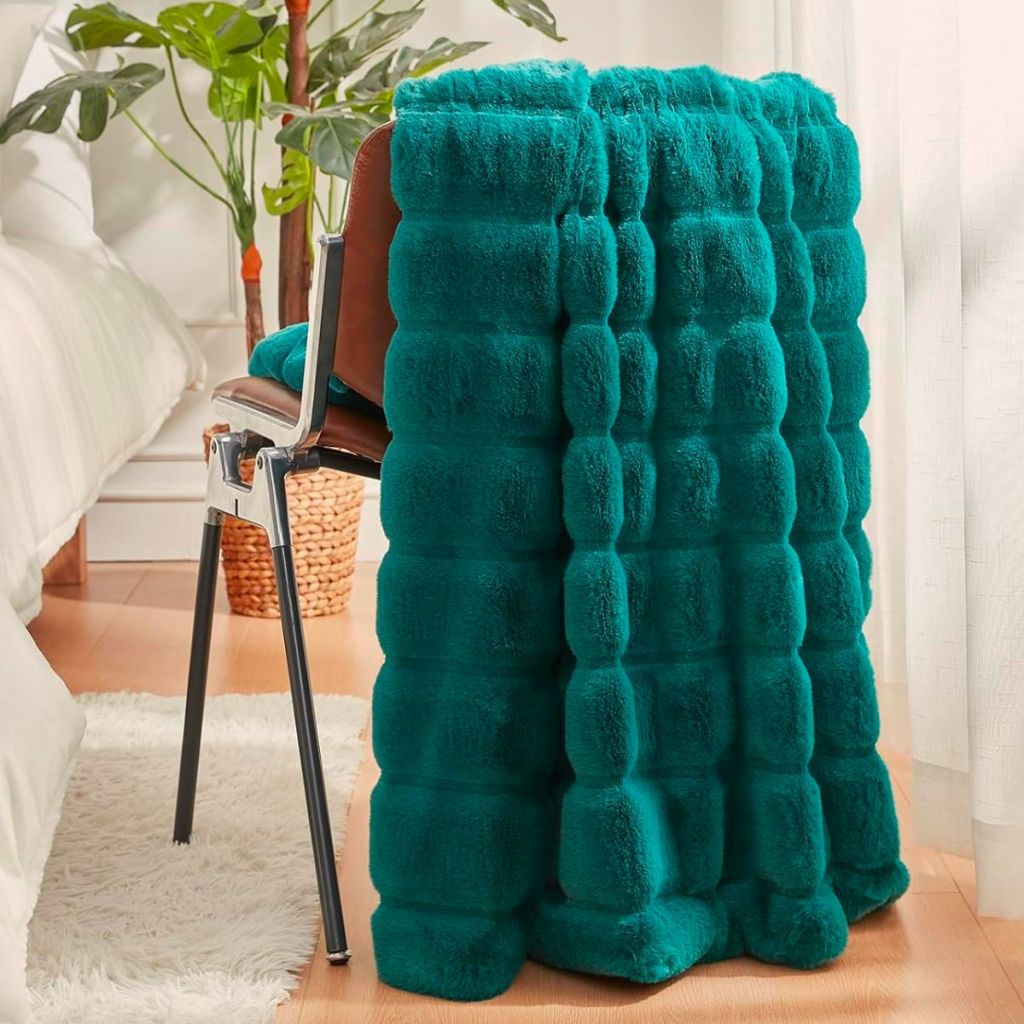 a Faux Fur Throw Blanket draped over the back of a chair in Peacock Green