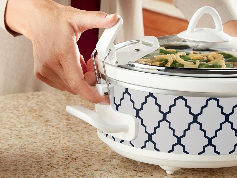 Hand latching the locks on a Crockpot Caserole Slow Cooker
