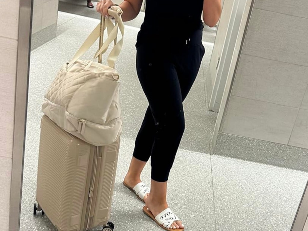 woman taking pic of beige weekender bag in airport mirror