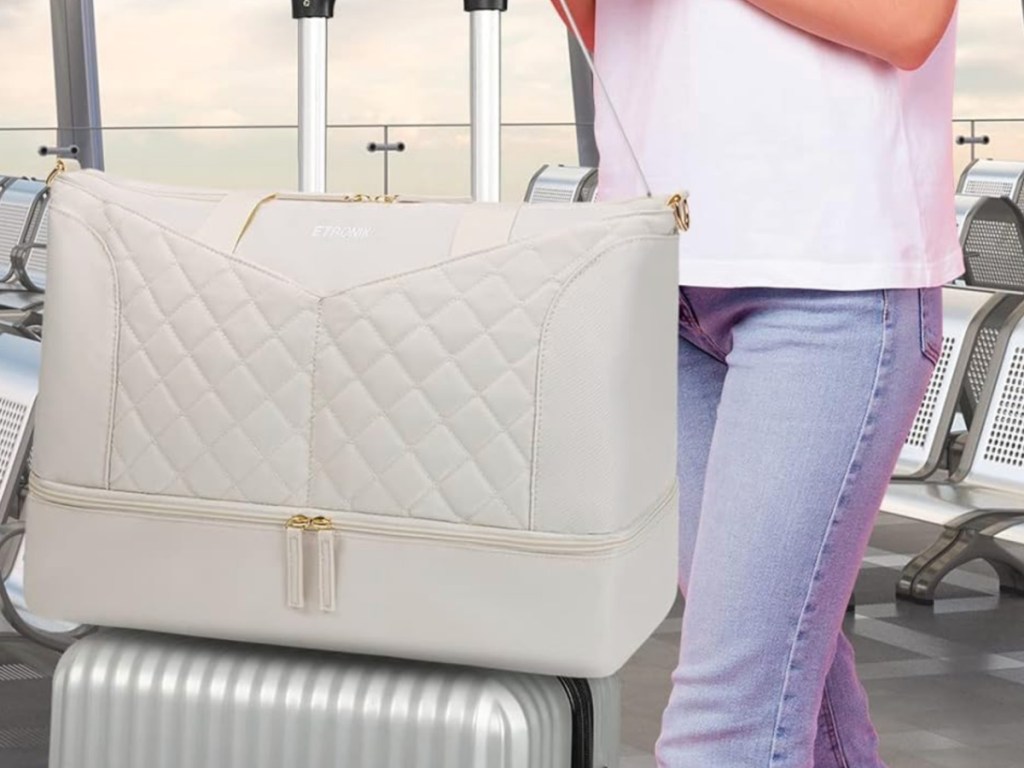 beige colored weekender bag on top of rolling luggage