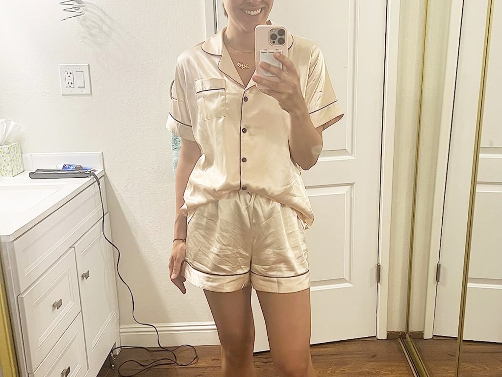 woman taking photo in mirror wearing white satin pajama set