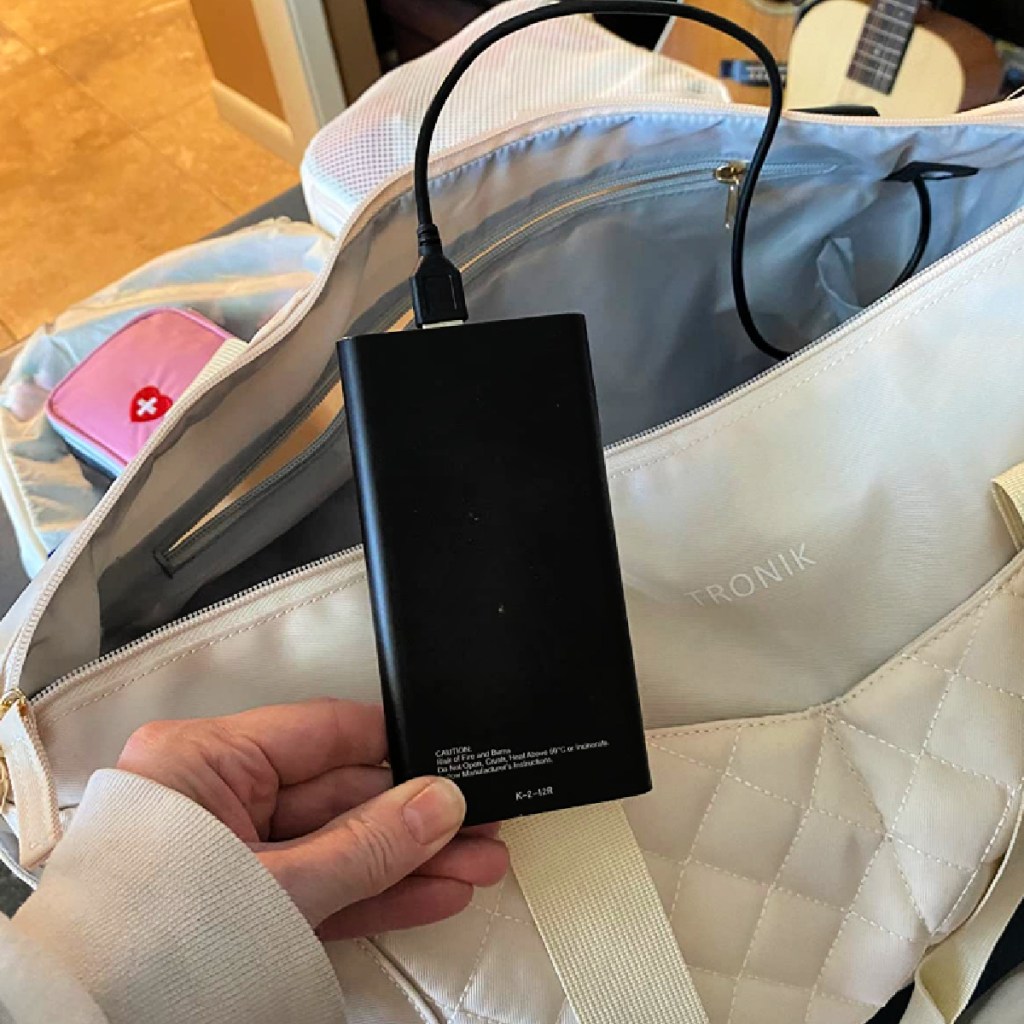 woman holding up charger threaded through Etronik bag with usb port