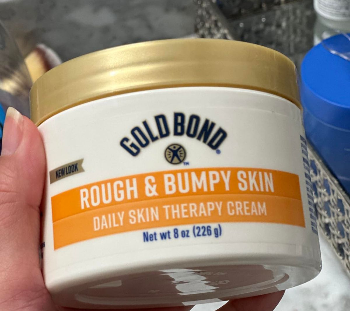 a hand holding a jar of moisturizer for rough and bumpy skin