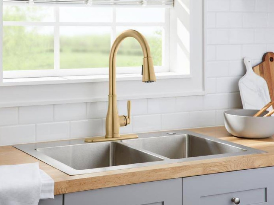 Gold kitchen faucet displayed on a gray kitchen sink