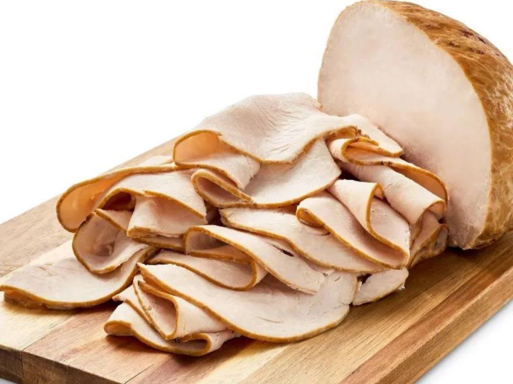 A cutting board with Good & Gather sliced deli turkey on it