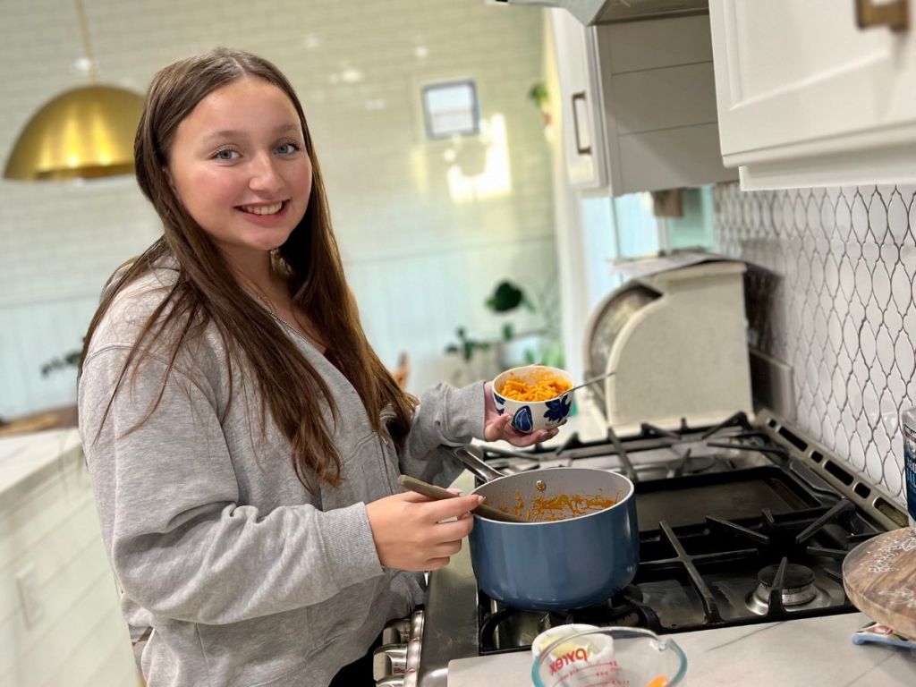 teen girl getting mac and cheese out of a pot on stove