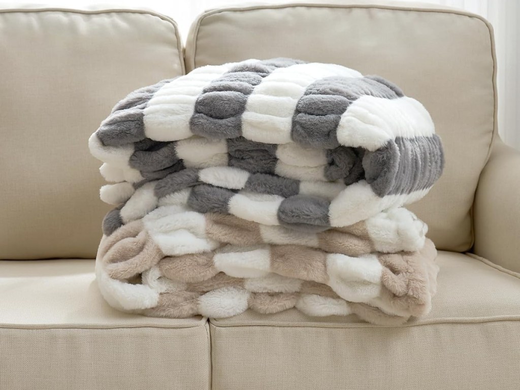Grey and white and tan and white throw blankets displayed on the couch