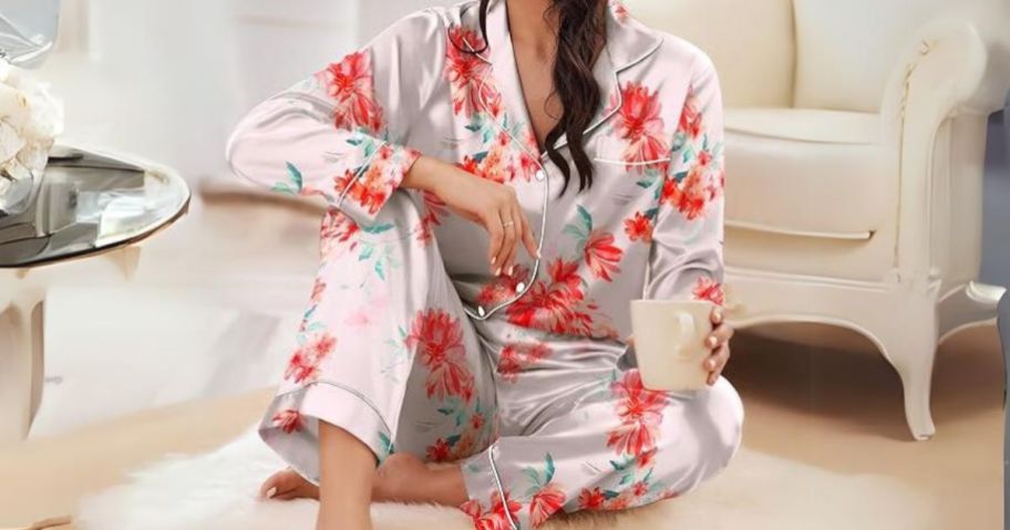 woman wearing a flower pattern satin pajama set sitting on floor with a cup of coffee