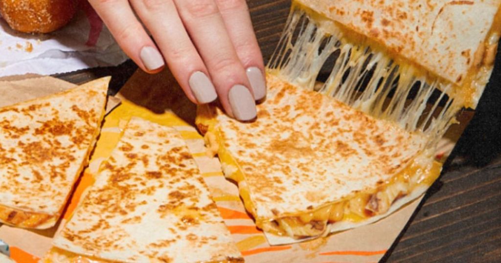 woman's hand picking up a slice of a Taco Bell chicken quesadilla