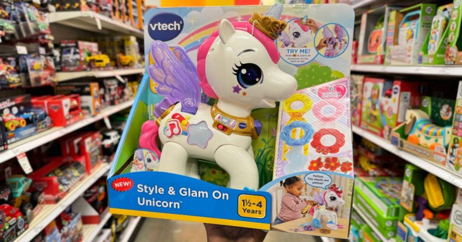 a womans hand displaying a VTech toy unicorn in Target