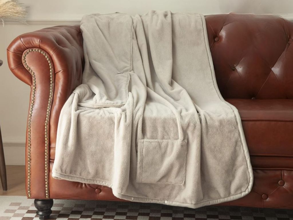 tan heated blanket shown thrown over brown leather sofa