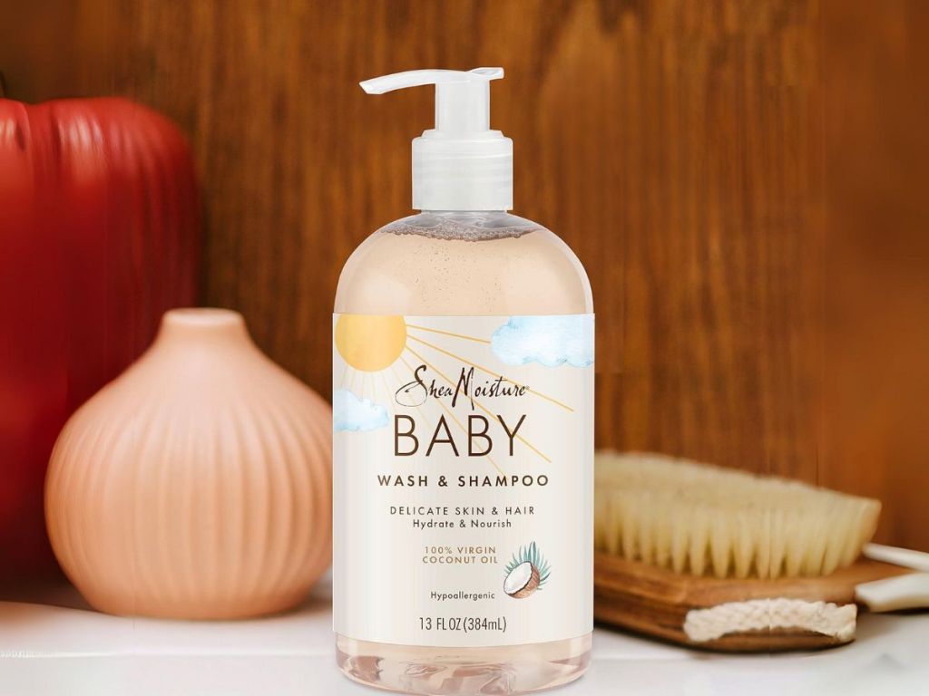 bottle of SheaMoisture Baby Wash and Shampoo on counter with hair brush and vase behind it