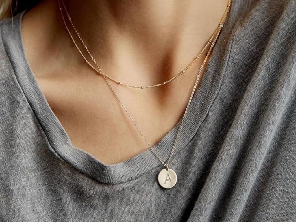 woman wearing a gold layered initial charm necklace with the letter 