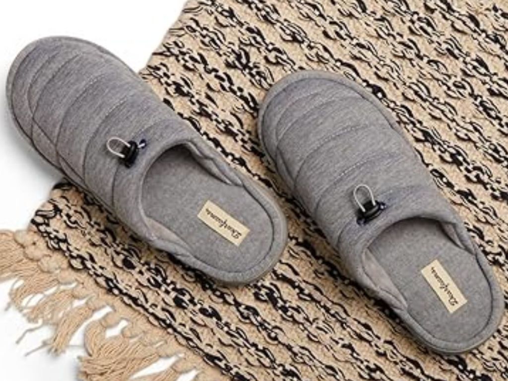 pair of grey men's Dearfoams slippers on a tan and black rug