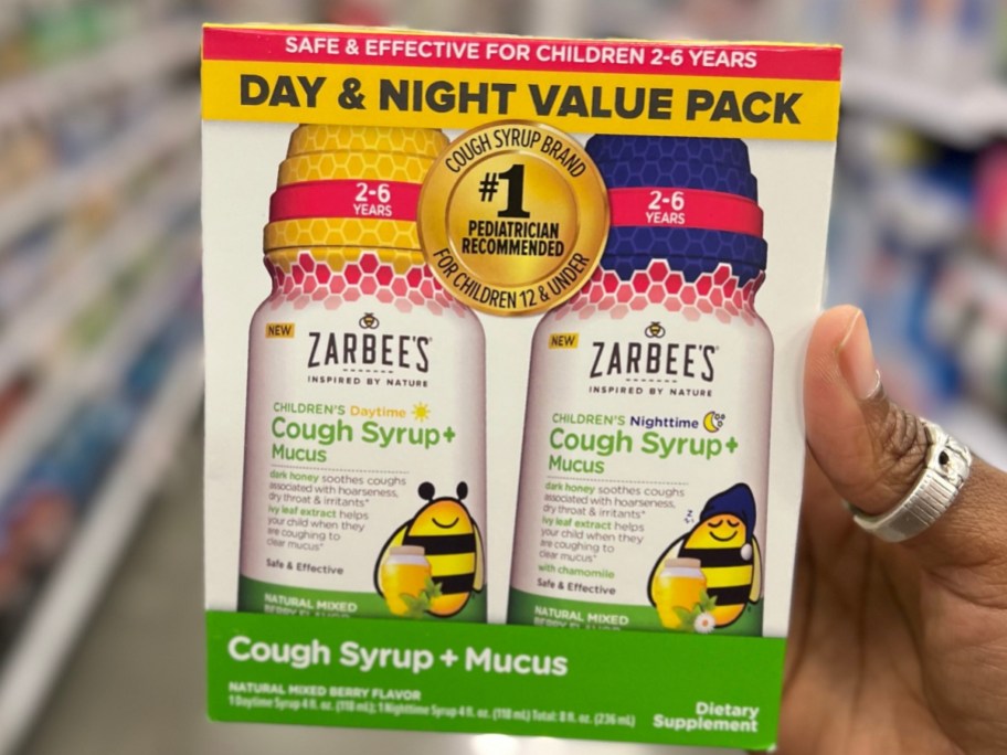 hand holding a box of Zarbee's Kids All-in-One Day/Night Cough Syrup