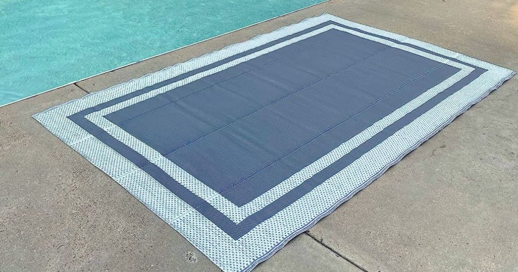grey and white outdoor rug on a patio beside a swimming pool