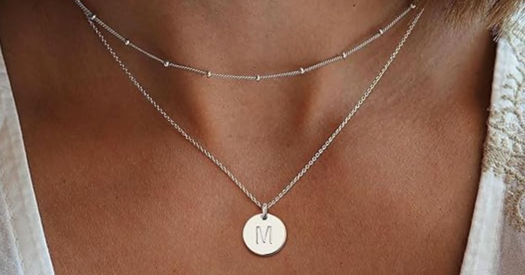 woman wearing a silver layered initial charm necklace with the letter 