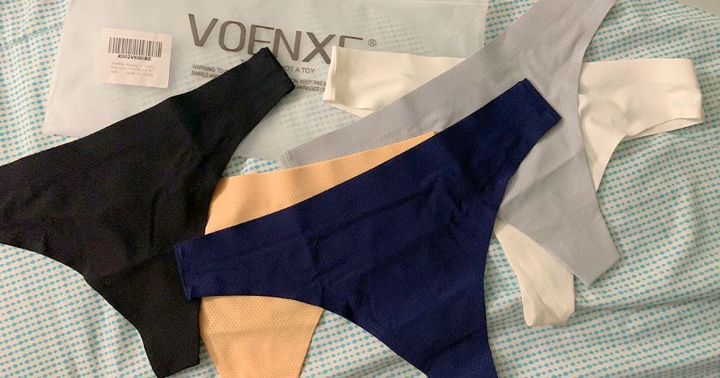 5 pairs of women's seamless thong panties laid out on bed with Voenxe packaging behind them