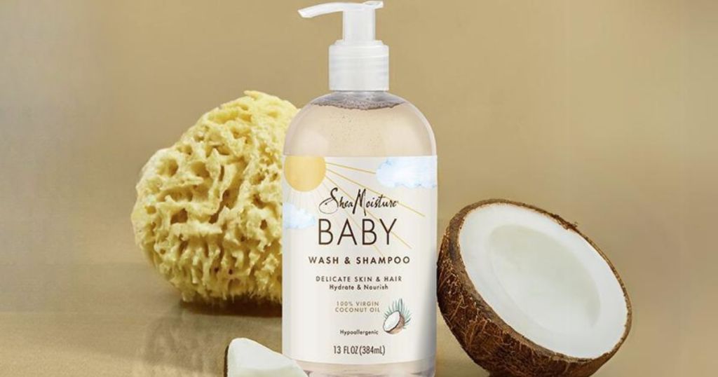 bottle of SheaMoisture baby wash and shampoo with an open coconut beside it and a loofah behind it