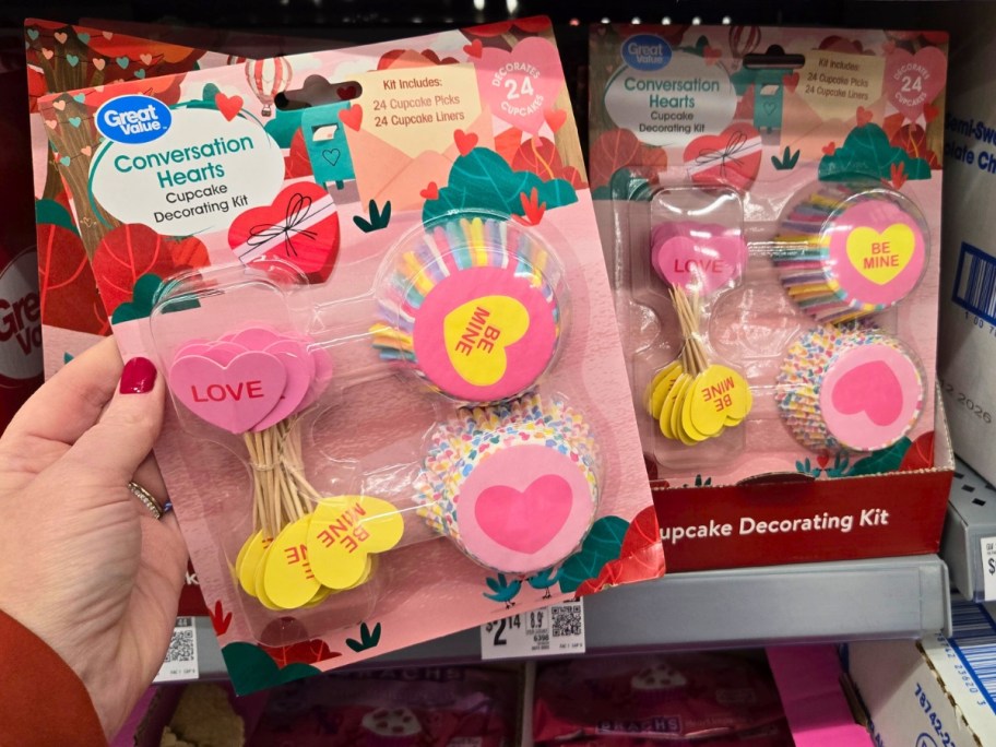 hand holding a Valentine's Day Cupcake decorating kit in a package, more on a store shelf behind it