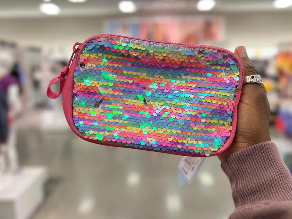 Hand holding multicolor fanny pack at a store