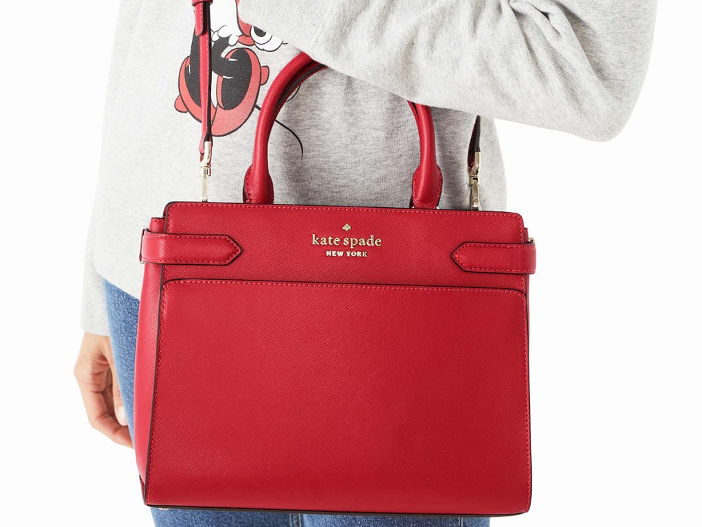 woman in a grey minnie mouse sweatshirt with a red kate spade satchel
