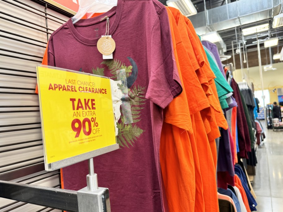 yellow 90% off clearance sign in front of rack of graphic tees