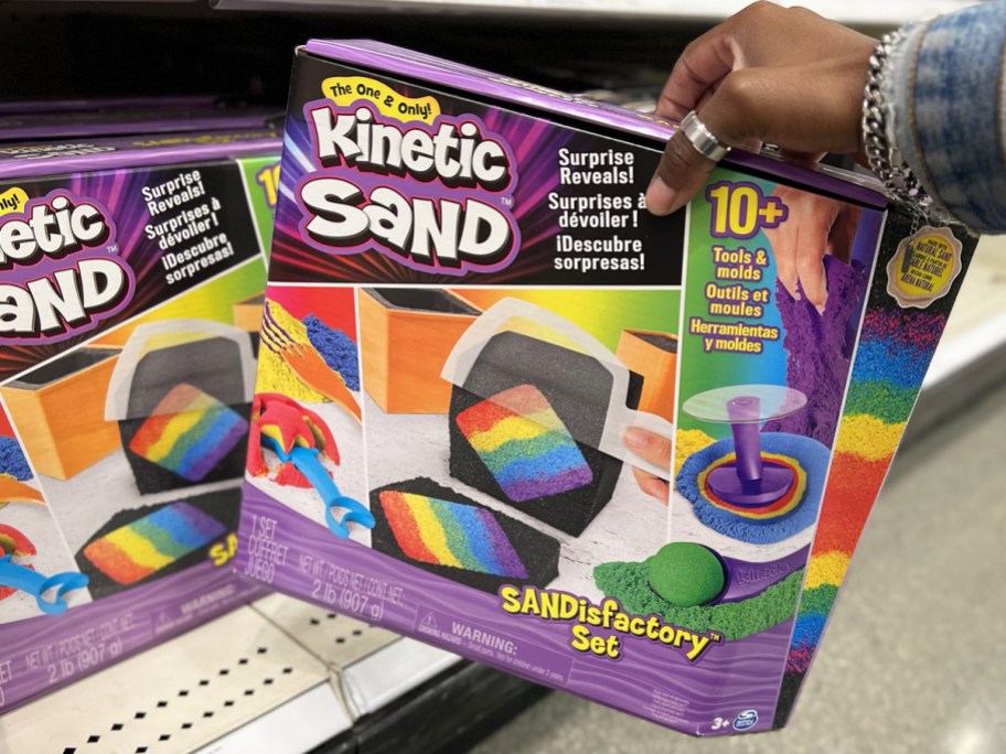 hand grabbing Kinetic Sand Sandisfactory Set from store shelf